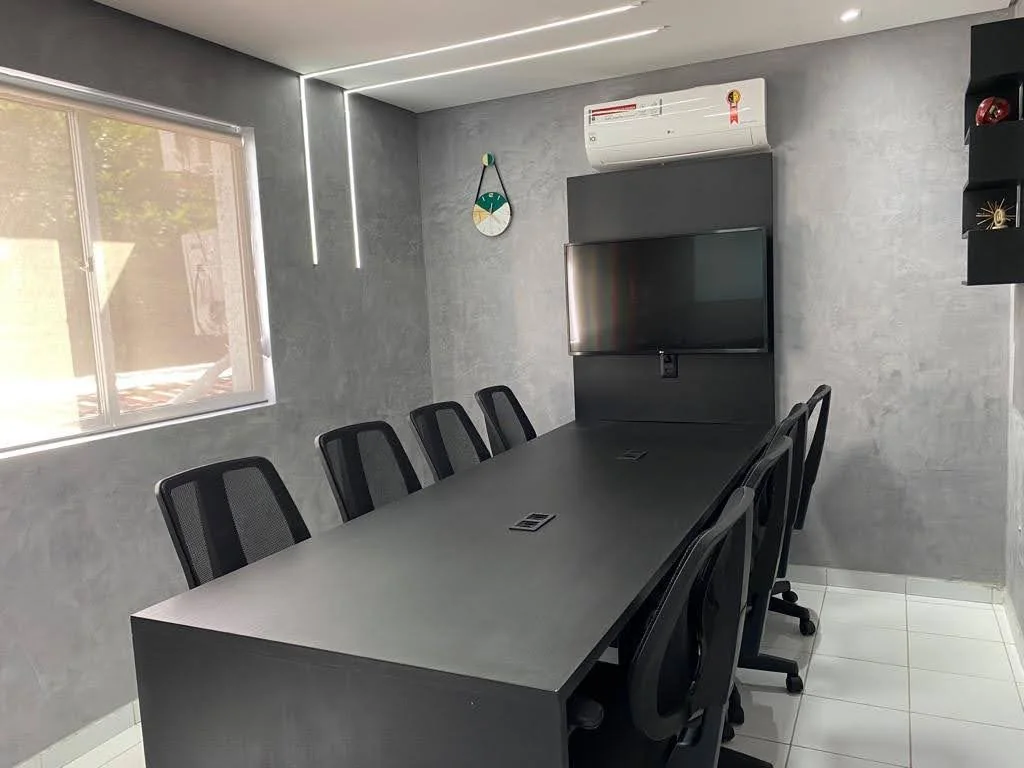 Sala de reunião da Classroom Graças: mesa para oito lugares, cadeiras executivas, TV de 43 polegadas e janela com luz natural